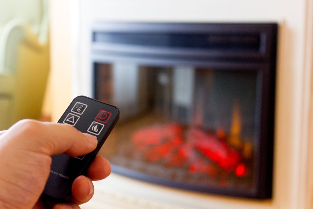 Electric fireplace remote control in human hand.