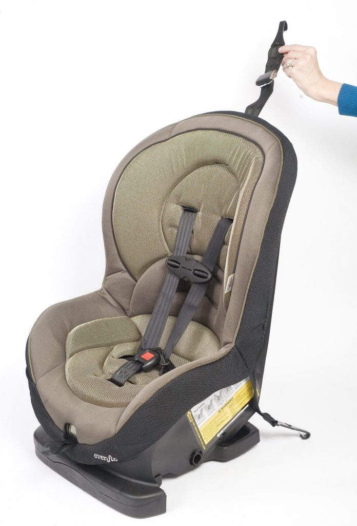 A hand holds up the tether strap on a car seat