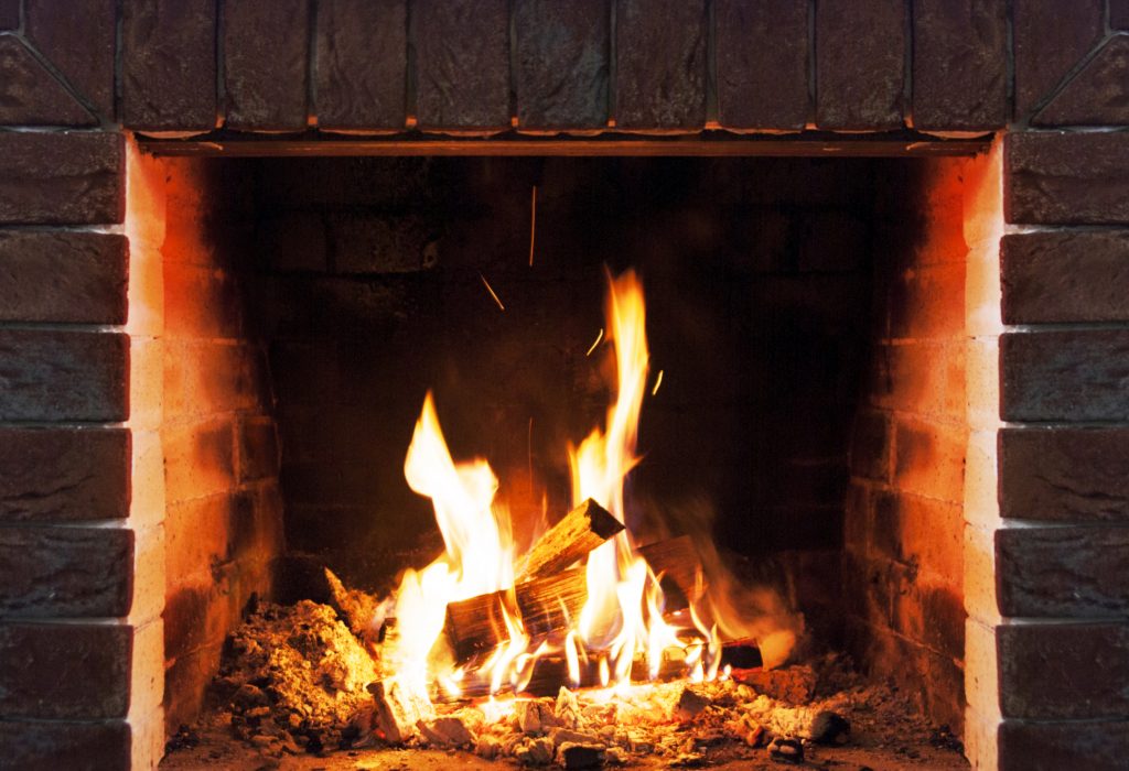 Close-up of wood logs and flames in a brick fireplace