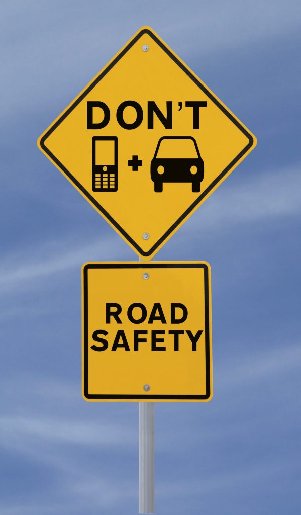 Two yellow signs stating don't text and drive; road safety in black lettering