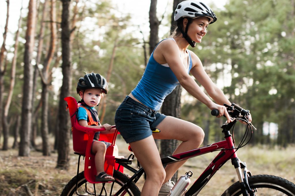 Woman riding bike with child in bike carrier